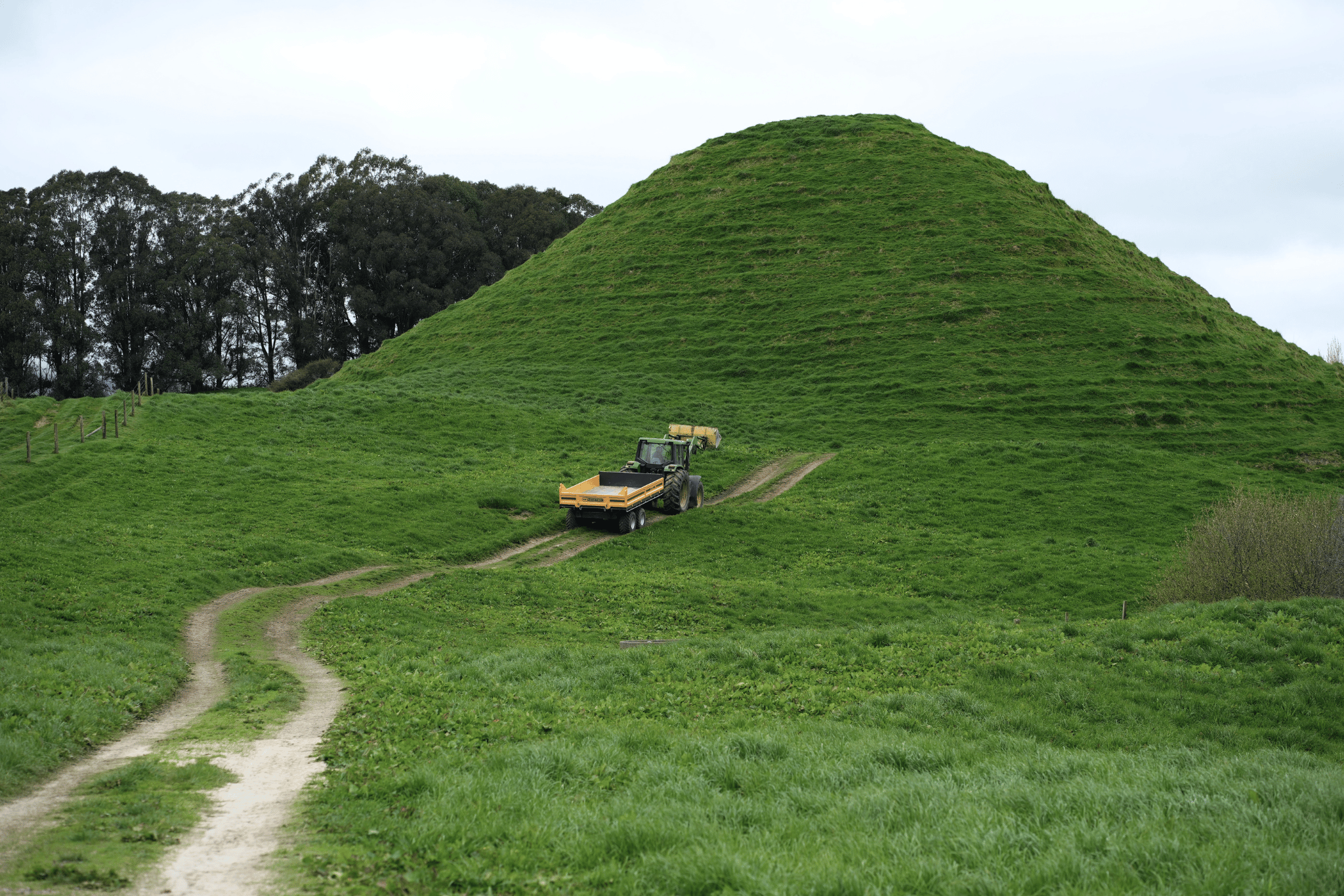 Tractor and Maxi trailer following a farm track across green hill country
